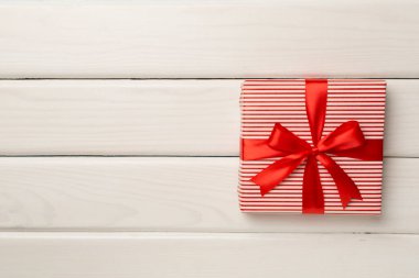 Kırmızı kurdeleli hediye kutusu ahşap arka planda, üst manzara.