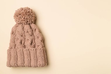 Brown winter hat with pompon on color background. Top view.