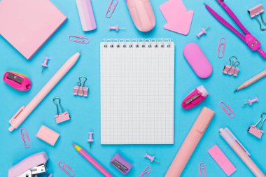 Renkli arka plan üzerine not defteri olan pembe okul kırtasiyesi, üst görünüm