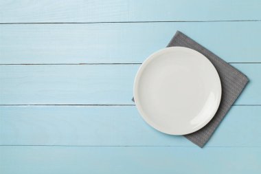 Tahta arka planda boş yuvarlak tabak, üst görünüm.