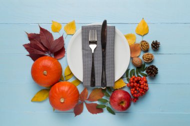 Çatal bıçak takımı, peçete ve ahşap arka planda sonbahar dekoru, üst manzara. Şükran Günü sofrası?