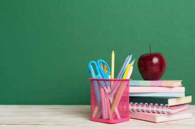 Ahşap masa üzerinde kitap ve kırtasiye malzemesi olan kompozisyon. Okul konseptine dönelim.