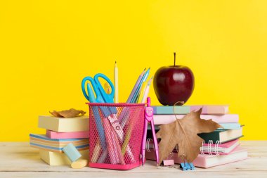 Ahşap masa üzerinde kitap ve kırtasiye malzemesi olan kompozisyon. Okul konseptine dönelim.