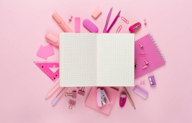 Renk arkaplanı ve üst görünümü üzerinde not defteri olan çeşitli okul kırtasiyesi