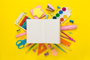 Renk arkaplanı ve üst görünümü üzerinde not defteri olan çeşitli okul kırtasiyesi