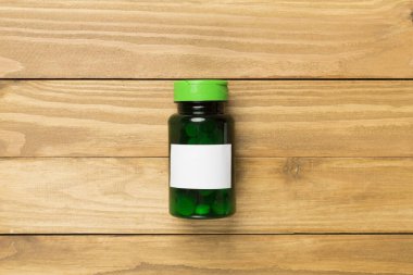 Ahşap zemin üzerinde vitaminler olan plastik şişe.