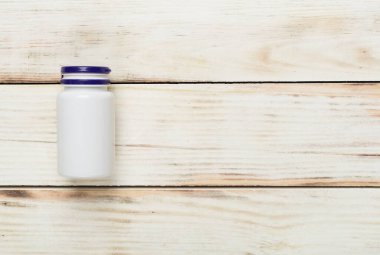 Ahşap zemin üzerinde vitaminler olan plastik şişe.