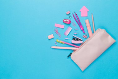 Renkli arka plan üzerinde okul kırtasiyesi olan pembe kalem kutusu, üst görünüm