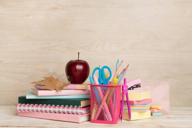 Ahşap masa üzerinde kitap ve kırtasiye malzemesi olan kompozisyon. Okul konseptine dönelim.