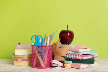 Ahşap masa üzerinde kitap ve kırtasiye malzemesi olan kompozisyon. Okul konseptine dönelim.