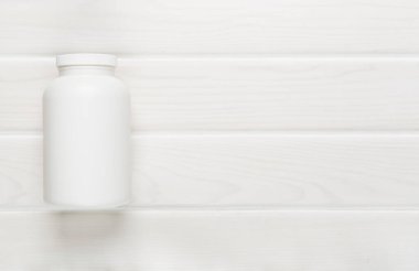 Ahşap zemin üzerinde vitaminler olan plastik şişe.