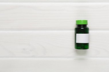 Ahşap zemin üzerinde vitaminler olan plastik şişe.