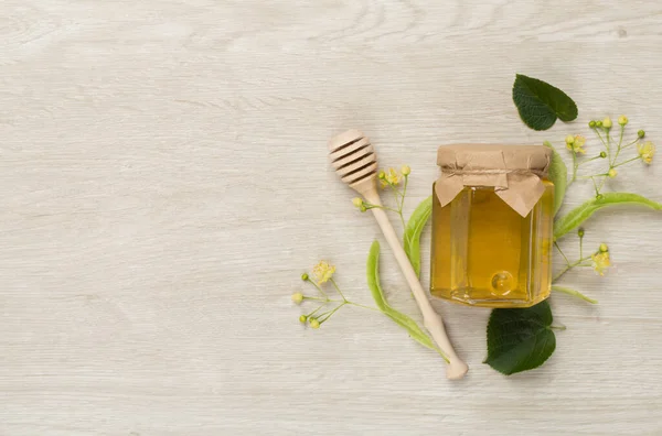 Linden honey with leaves and flowers on wooden backgroung, top view