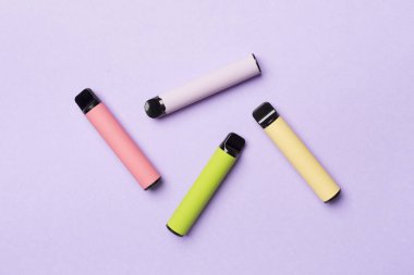 Disposable electronic cigarettes on color background, top view