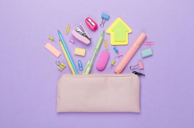 Renkli arka plan üzerinde okul kırtasiyesi olan pembe kalem kutusu, üst görünüm