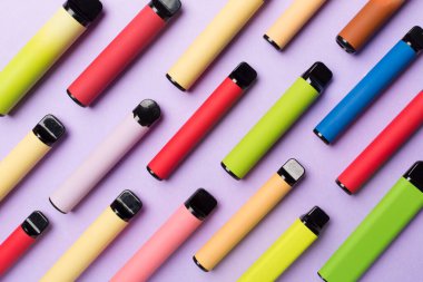 Disposable electronic cigarettes on color background, top view