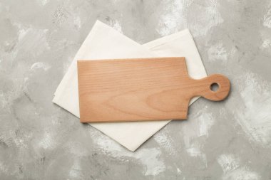 Beton zemin üzerinde havlu ile kesme tahtası, üst görünüm.