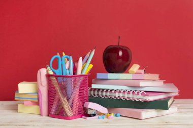 Ahşap masa üzerinde kitap ve kırtasiye malzemesi olan kompozisyon. Okul konseptine dönelim.