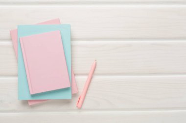 Ahşap zemin üzerinde kalem olan defterler, üst görünüm