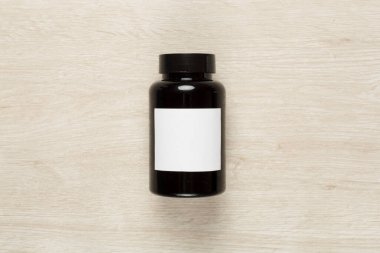 Ahşap zemin üzerinde vitaminler olan plastik şişe.