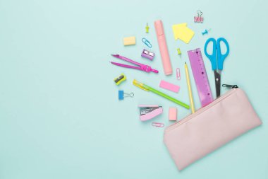 Renkli arka plan üzerinde okul kırtasiyesi olan pembe kalem kutusu, üst görünüm