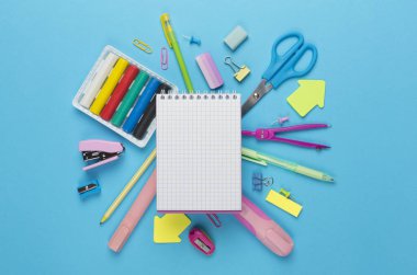 Renk arkaplanı ve üst görünümü üzerinde not defteri olan çeşitli okul kırtasiyesi