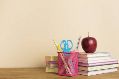Ahşap masa üzerinde kitap ve kırtasiye malzemesi olan kompozisyon. Okul konseptine dönelim.