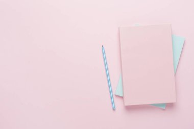 Renk arkaplanında kalem bulunan defterler, üst görünüm