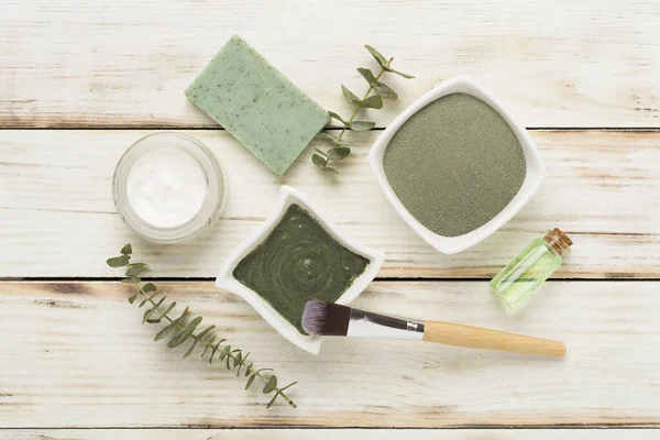 Composition with cosmetic clay and spa products on wooden background, top view