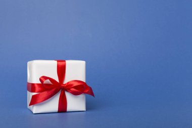 Arkaplanda kırmızı kurdele olan hediye kutusu.