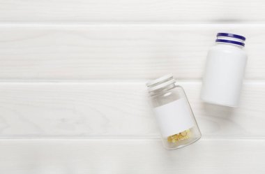 Ahşap zemin üzerinde vitaminler olan plastik şişeler.