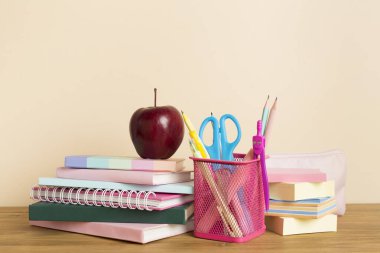 Ahşap masa üzerinde kitap ve kırtasiye malzemesi olan kompozisyon. Okul konseptine dönelim.