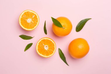 Flat lay with fresh oranges and leaves on color background.