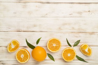 Flat lay with fresh oranges and leaves on wooden background.