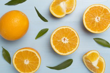 Flat lay with fresh oranges and leaves on wooden background.