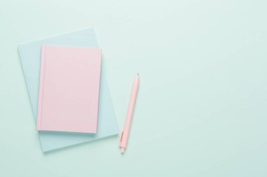 Renk arkaplanında kalem bulunan defterler, üst görünüm