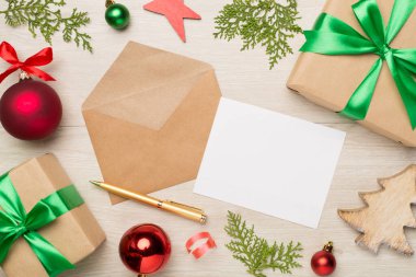 Ahşap arka planda noel süslemesi olan el işi zarf, üst görünüm.