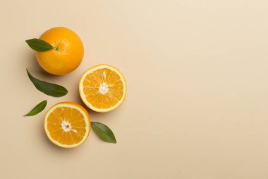Flat lay with fresh oranges and leaves on color background.