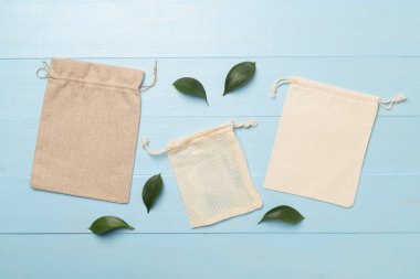 Small eco sacks with green leaves wooden on background. Top view