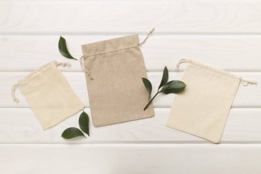 Small eco sacks with green leaves wooden on background. Top view