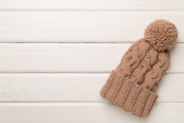 Brown winter hat on wooden background. Top view
