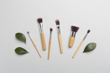 Natural biodegradable makeup brushes on color background, top view