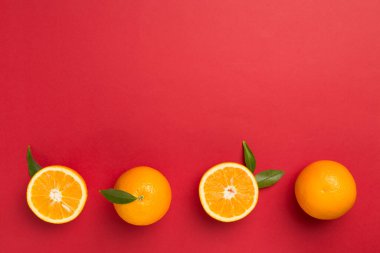 Flat lay with fresh oranges and leaves on color background.