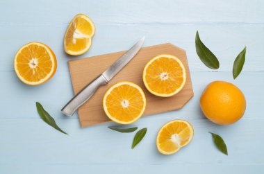 Flat lay with fresh oranges and leaves on wooden background.