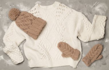 Sweater and winter hat withmittens on light background, top view