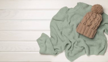 Sweater and winter hat withmittens on light background, top view