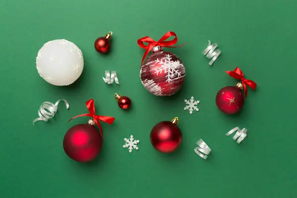 Christmas ball toys and confetti on color background, top view.