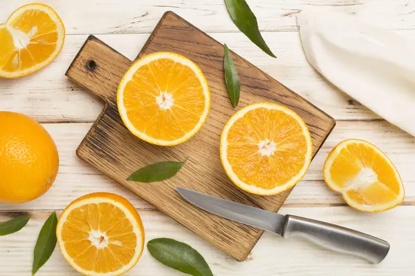 Flat lay with fresh oranges and leaves on wooden background.