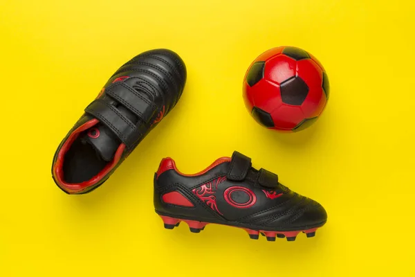 Football shoes with ball on color background, top view
