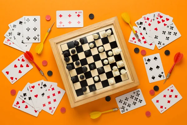 Different board games on color background, top view
